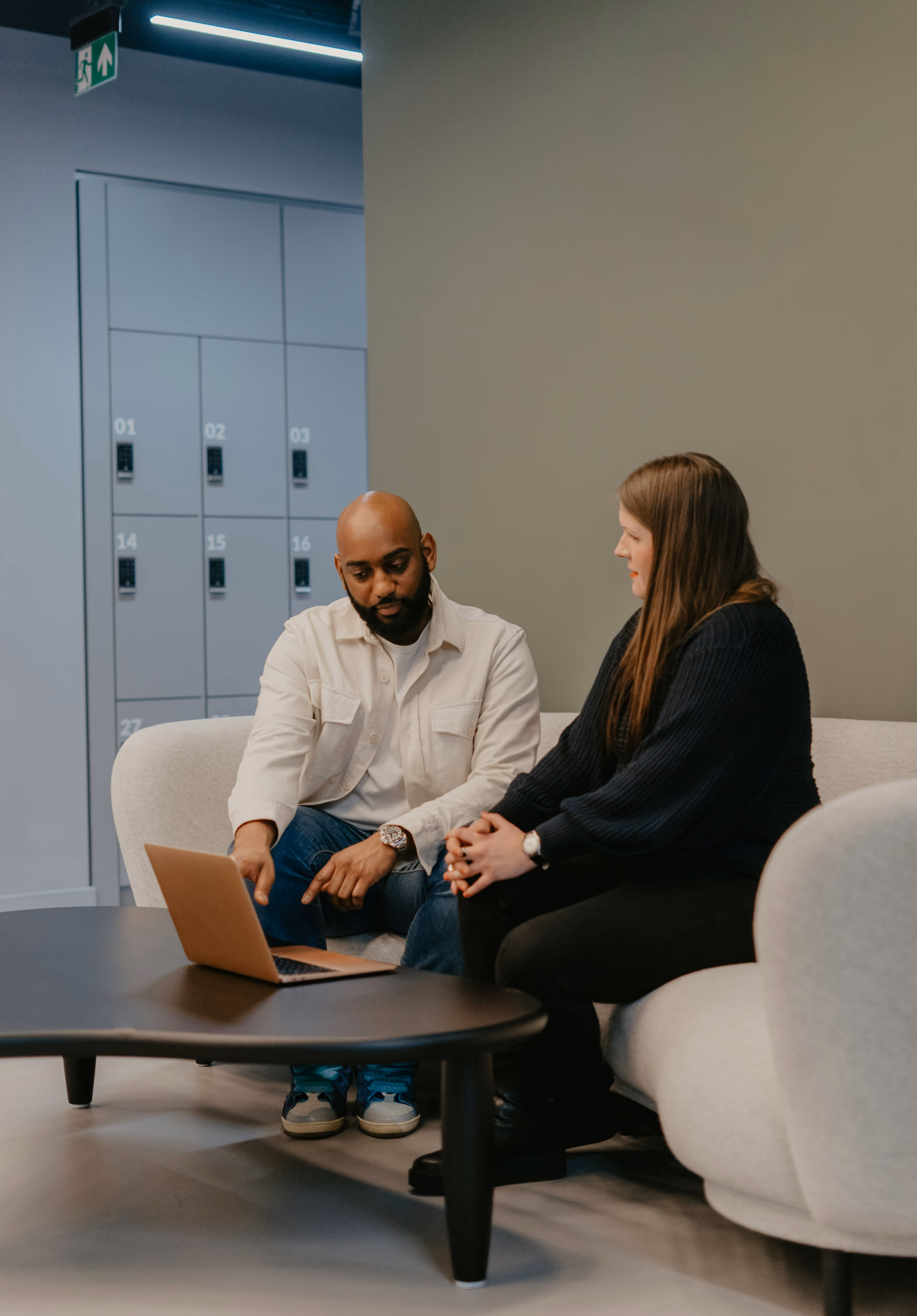 Two people sit on a couch looking at a computer
