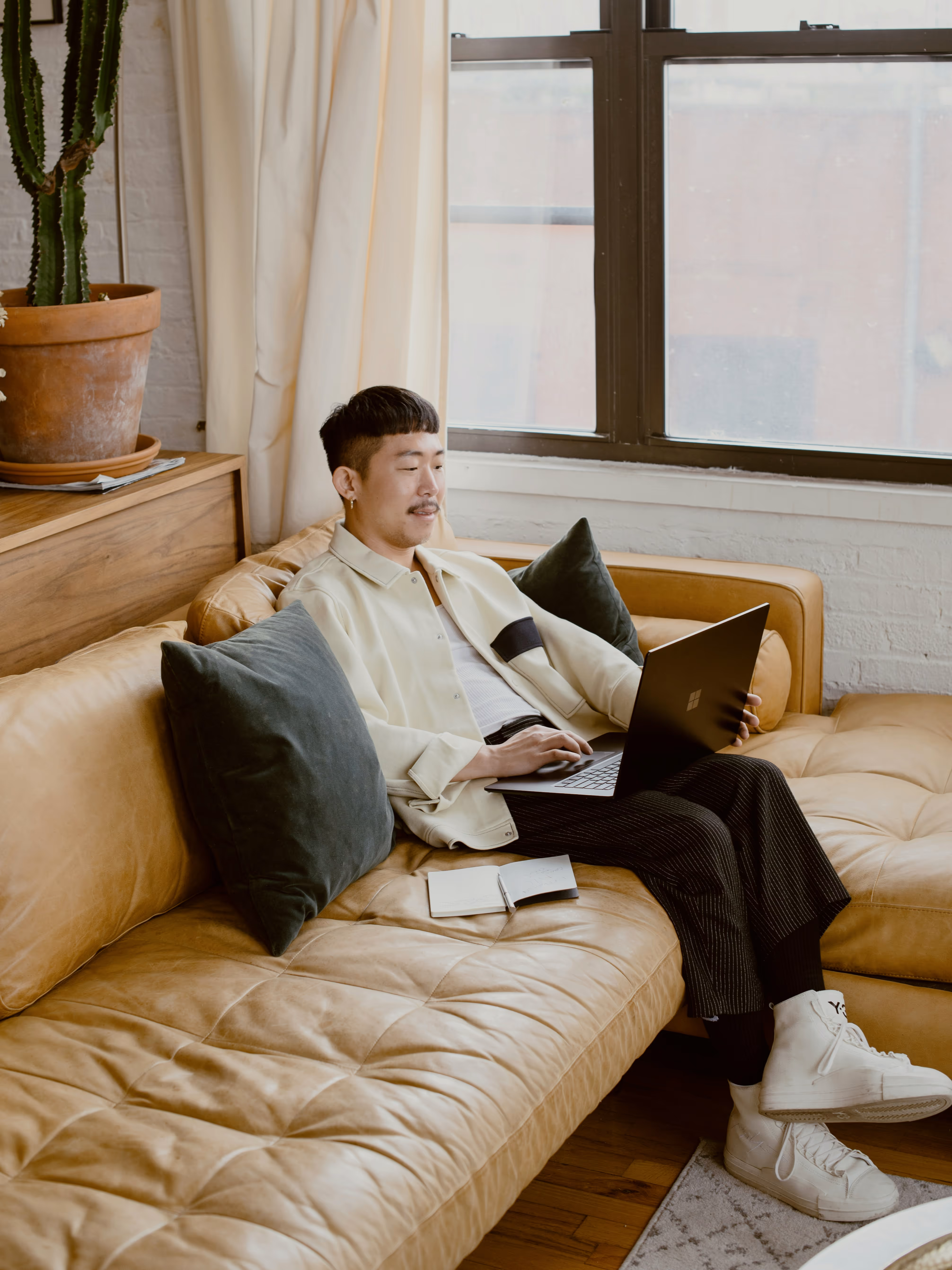 Man sits on a couch working on his computer