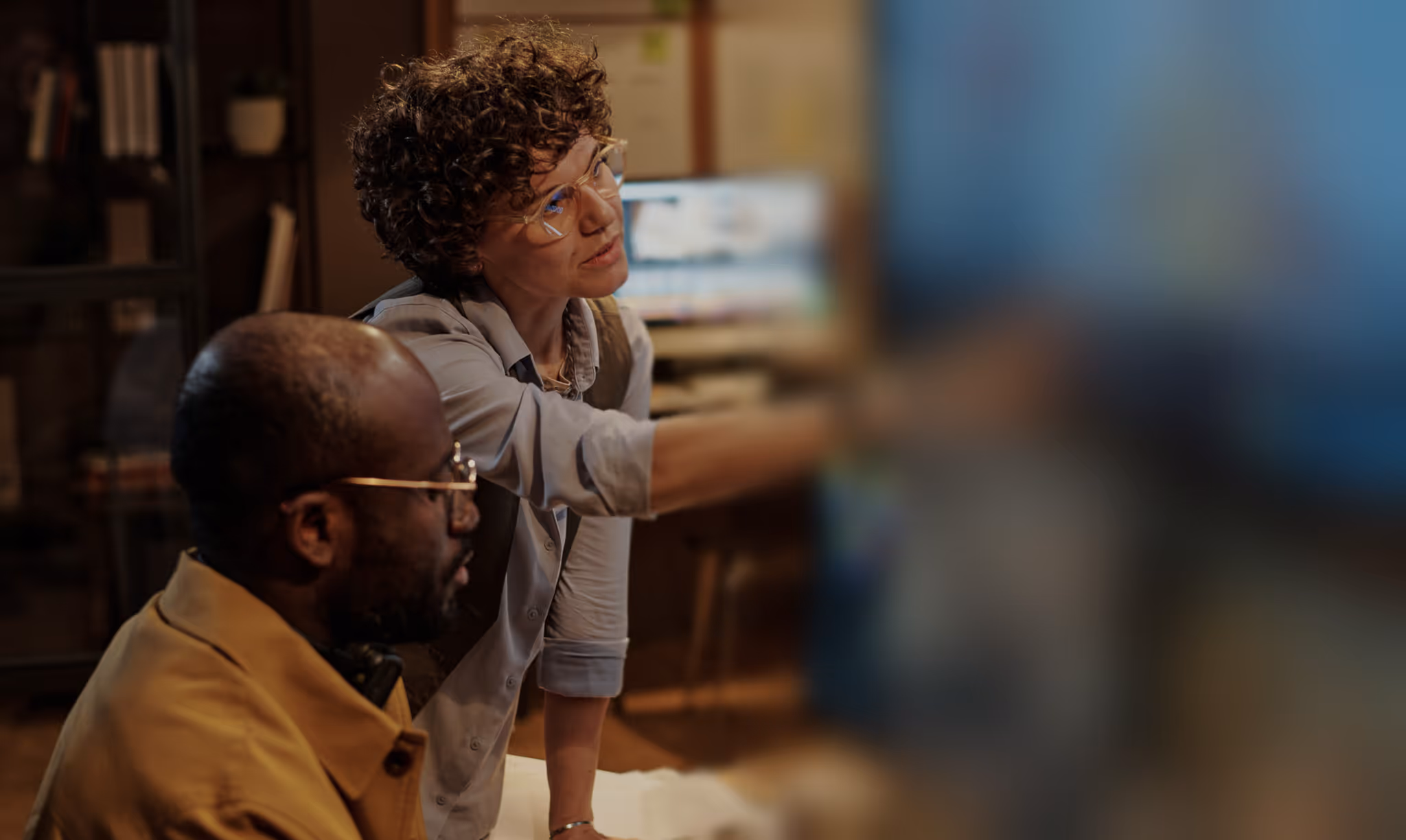 Woman explains something to a man on a computer with blur effect