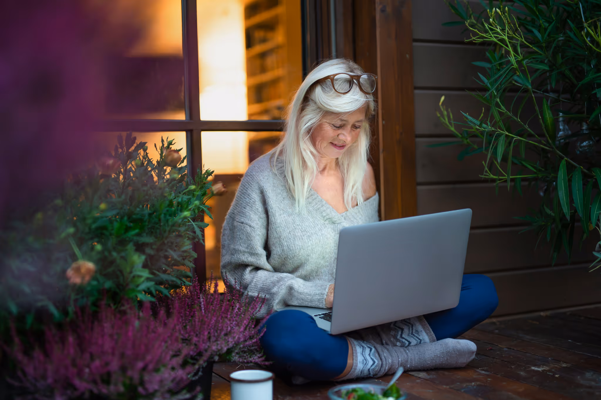 A lady sits in front of her house working on her computer