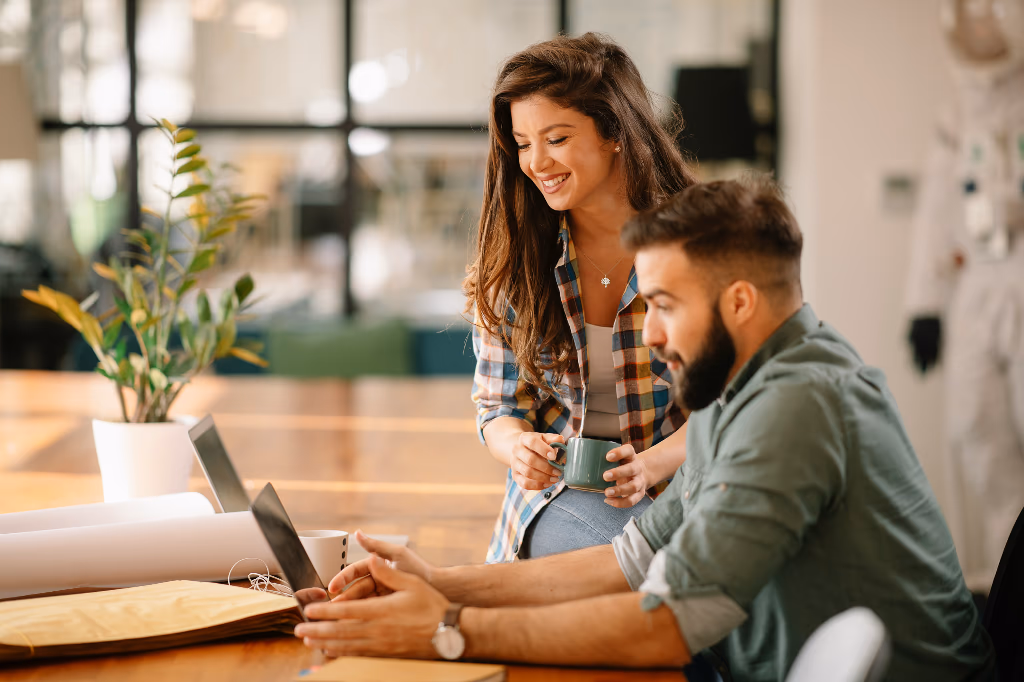 Two people working together on their computers in a office setting