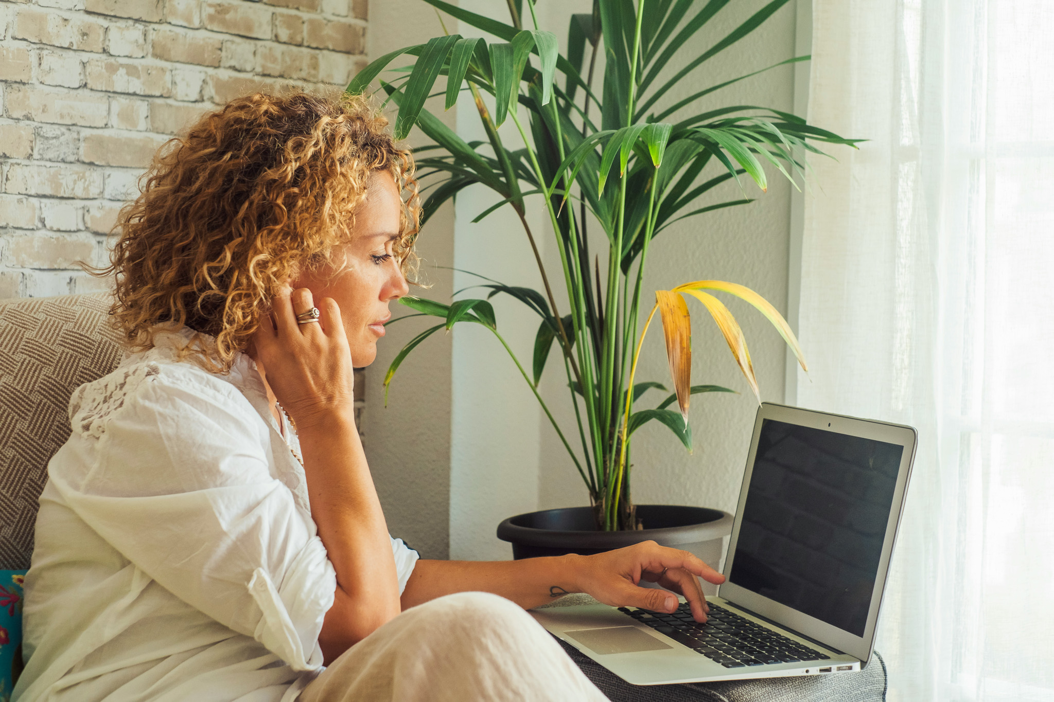 A woman sitting on a couch working on her computer