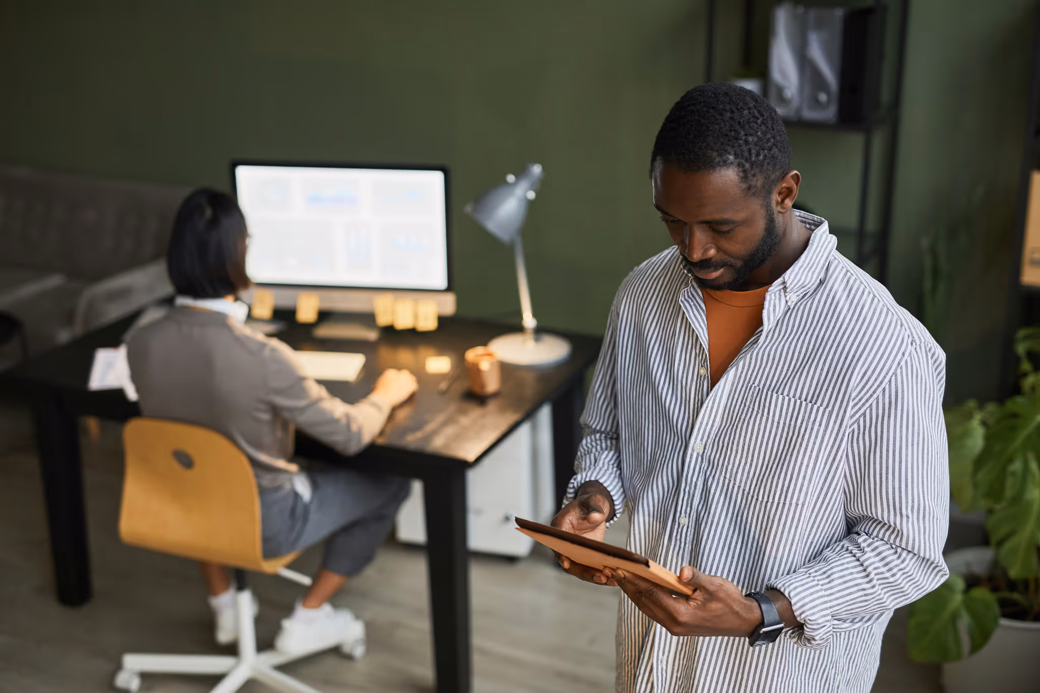 Two people working in an office on an tablet and computer