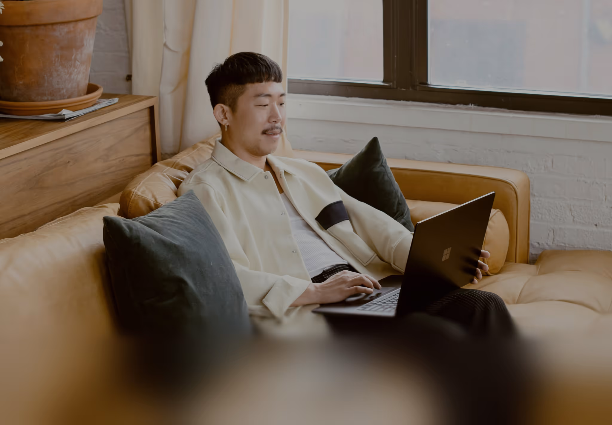 Blur effect on asian man working on his computer sitting on a couch