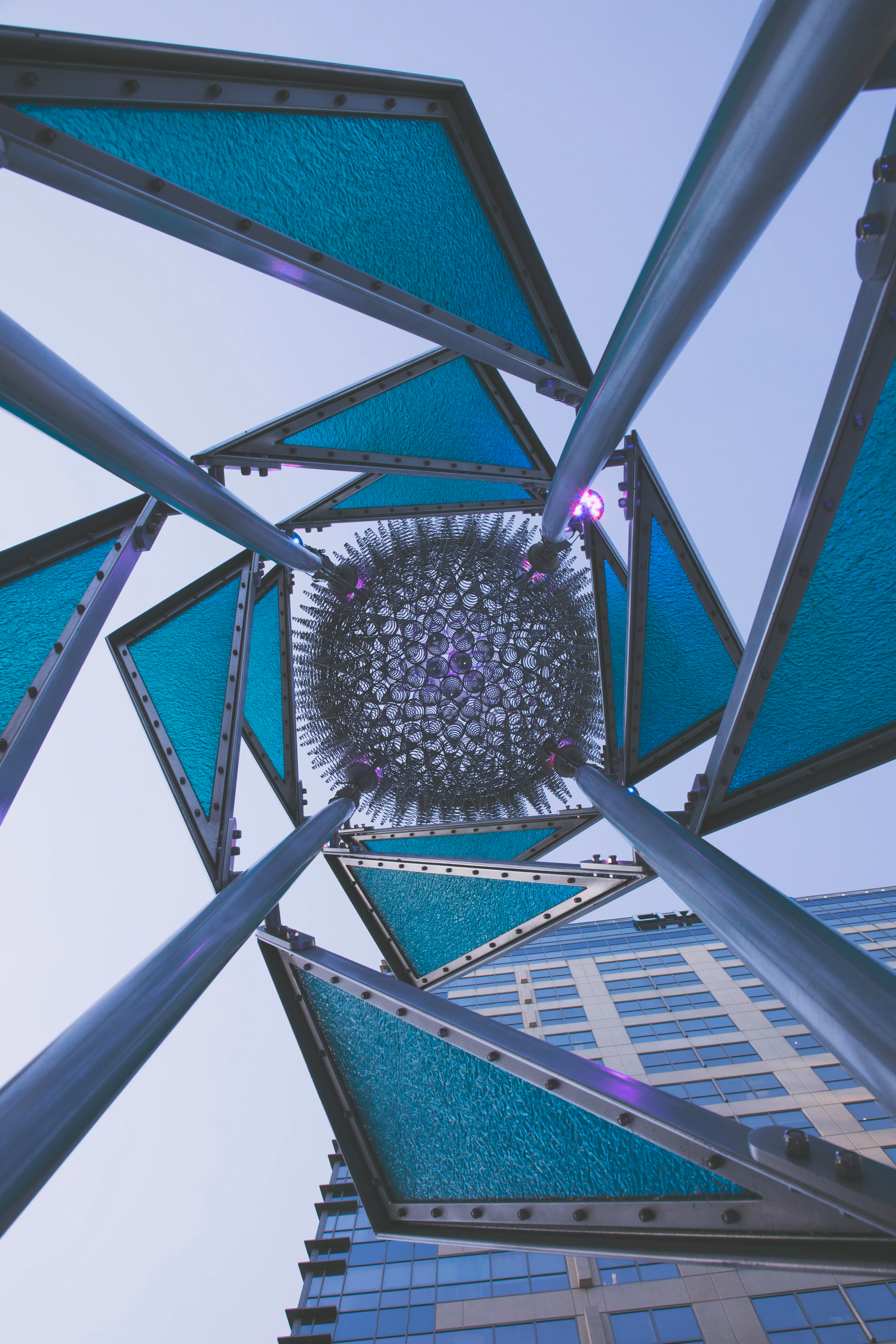 Teal glass public art sculpture against a city skyline, photography by DCG Visuals