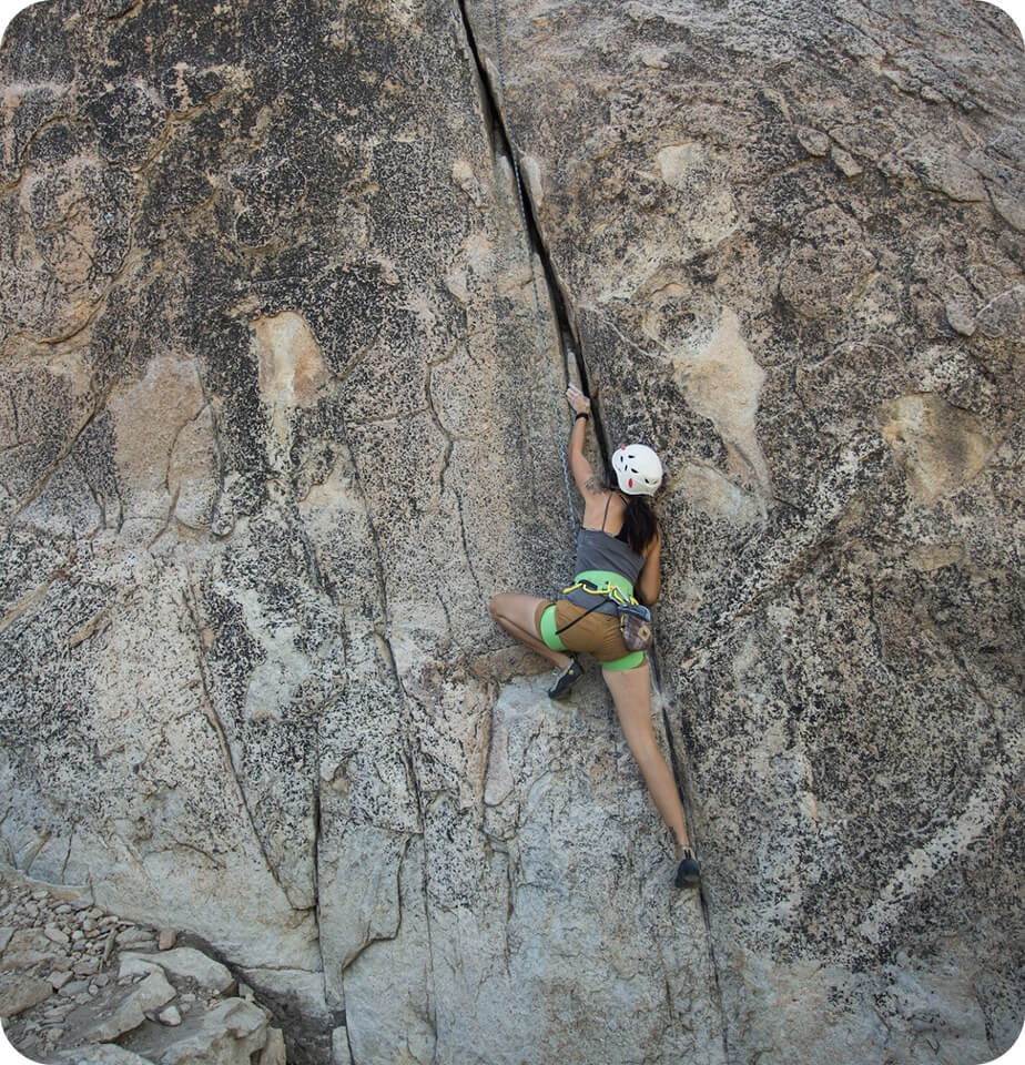 woman climbing rockface - outdoor athlete services