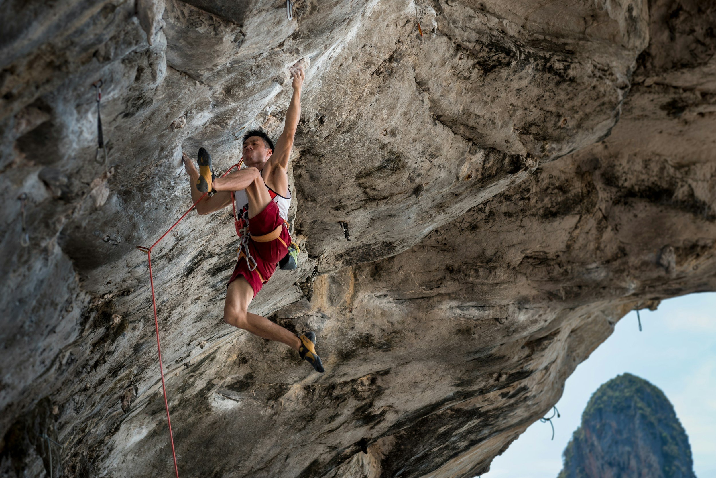 An athlete climbing a hard route and showcasing his upper body hanging strength