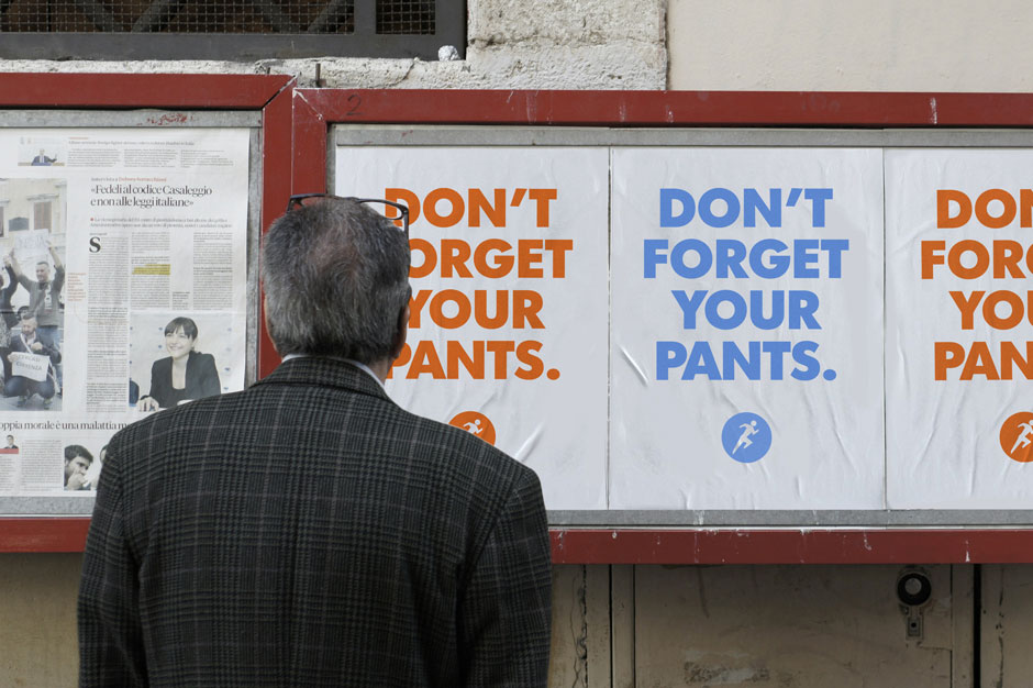 A man reads a public service announcement about running to work that says "Don't forget your pants."