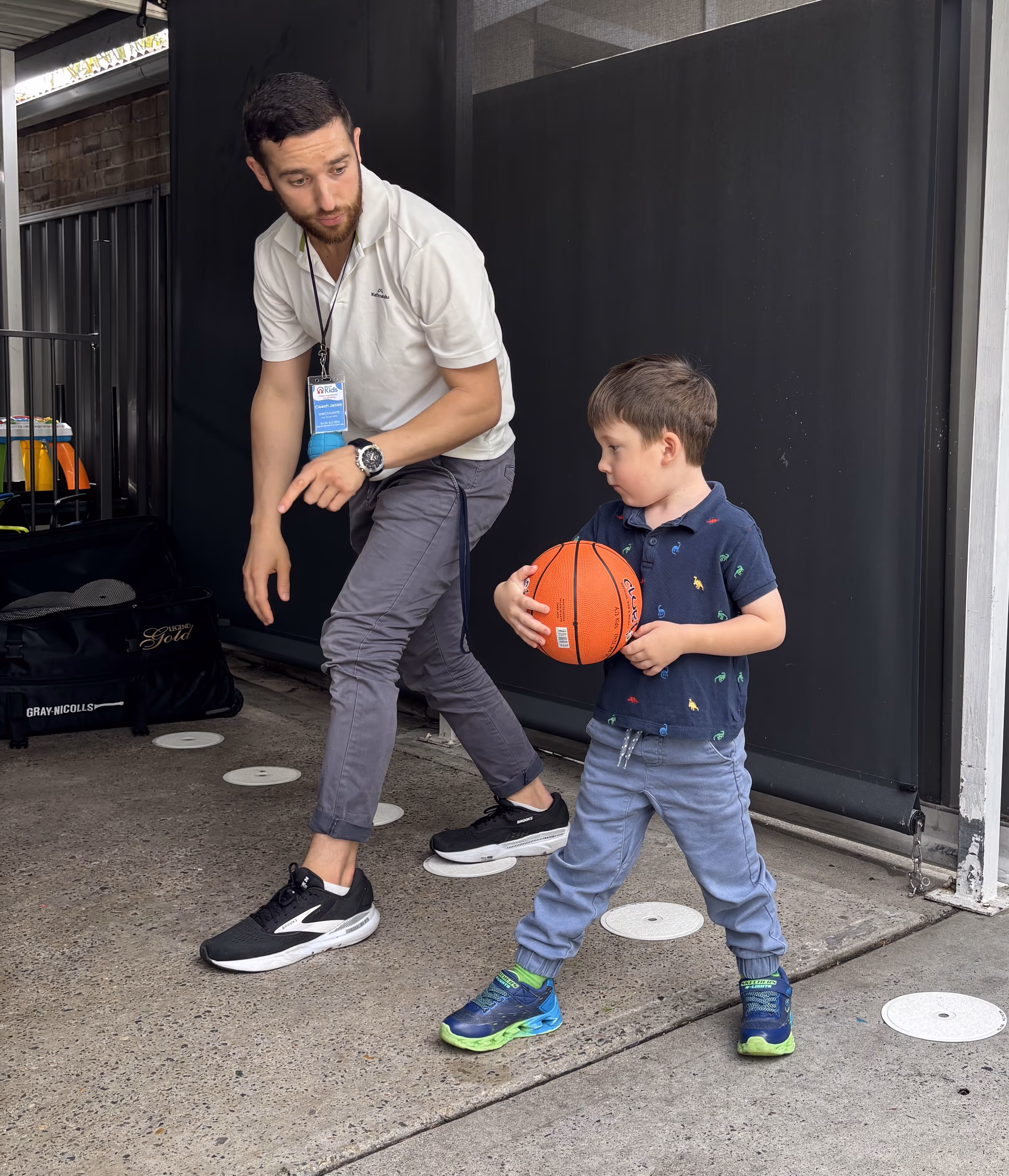 Coach teaches a kid how to dribble a ball