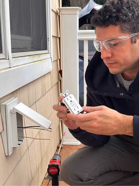 Digital Electric technician inspecting a wall-mounted control unit with a screwdriver.
