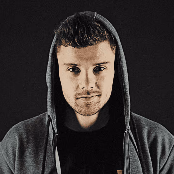 Junger Mann mit kurzen Haaren und Kapuzenpullover vor schwarzem Hintergrund.