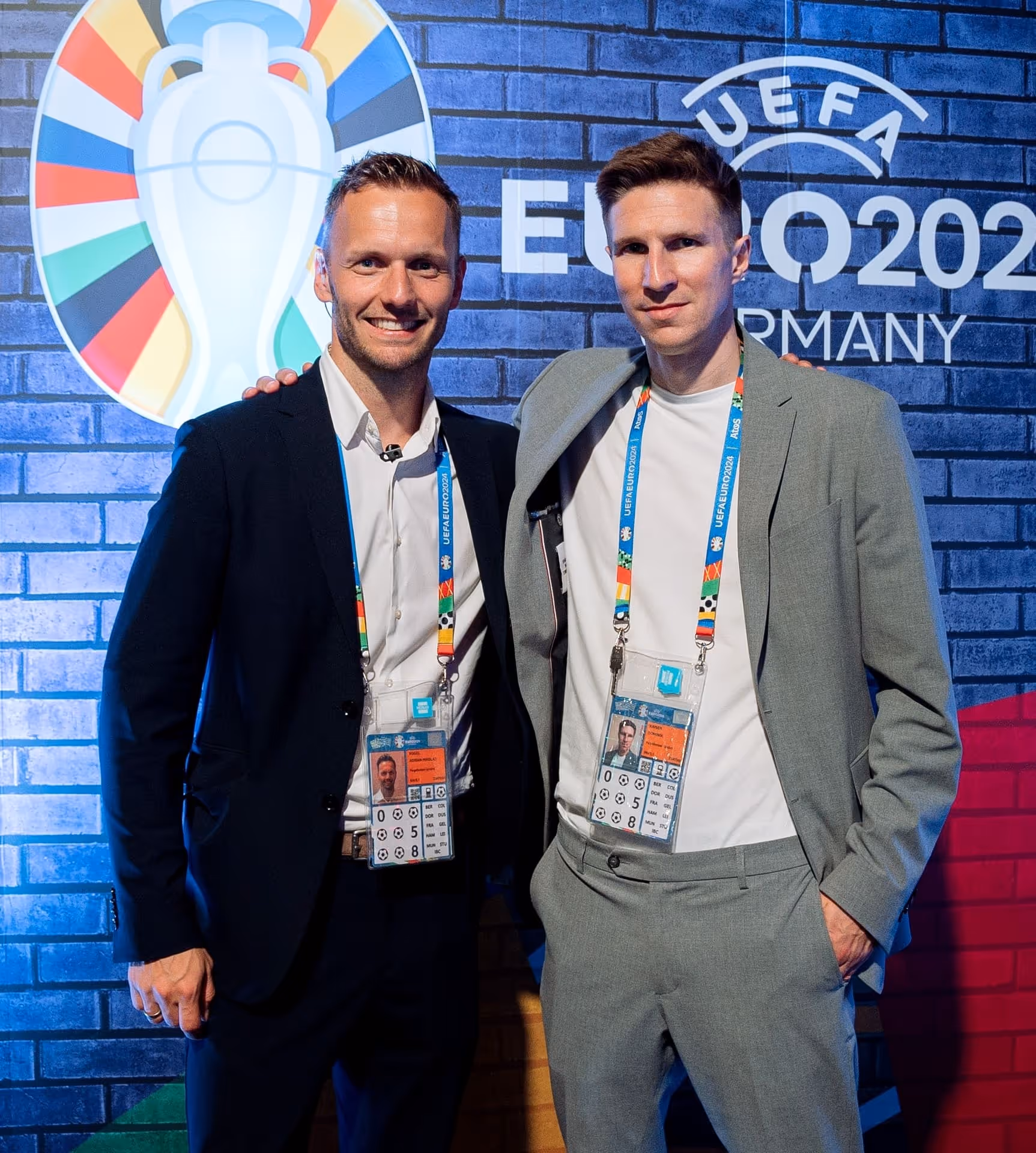 Zwei Männer mit UEFA EURO 2020 Ausweisen posieren vor einer Wand mit UEFA EURO 2020 Branding.