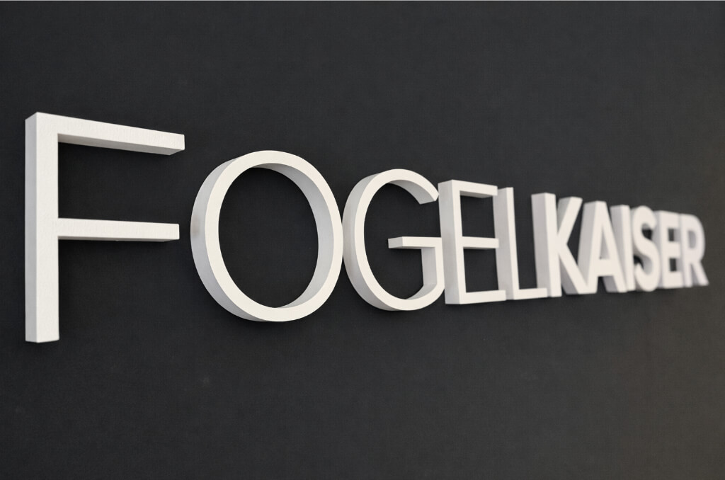 3D-Buchstaben mit der Aufschrift FOGELKAISER an einer schwarzen Wand.