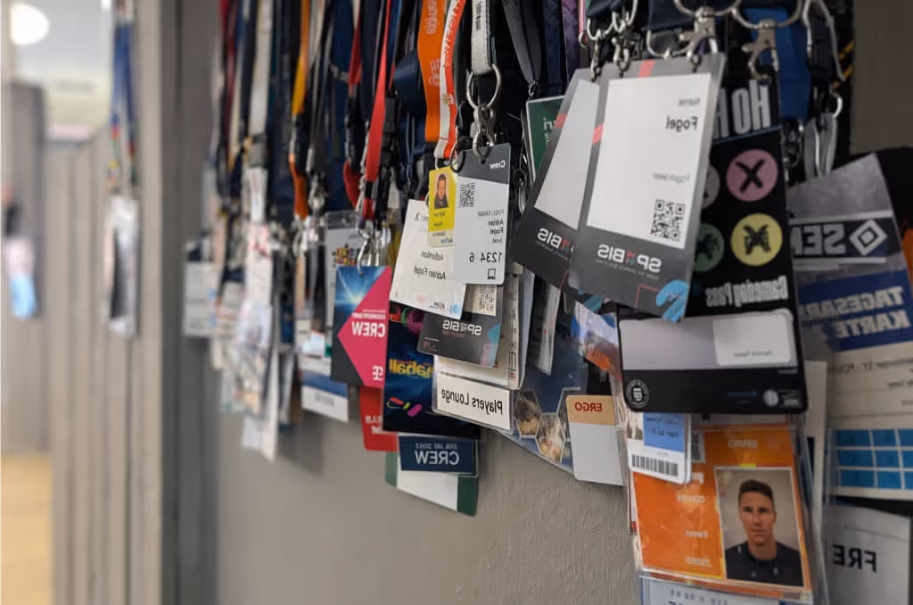 Verschiedene Veranstaltungs- und Mitarbeiterausweise hängen an einer Wand in Reihen.