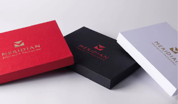 Three closed rectangular packaging boxes in red, black, and white with the Meridian Speciality Packaging logo on top.