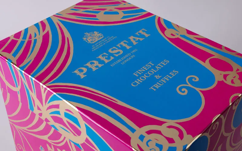 Box of Prestat finest chocolates and truffles with blue, pink, and gold ornate packaging design.
