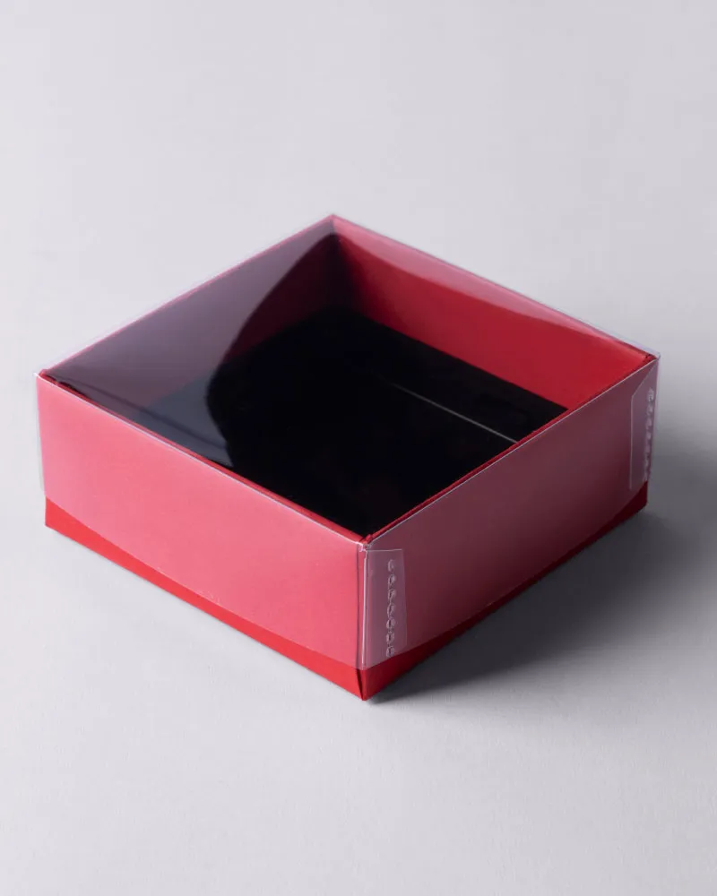 Square red cardboard box with a transparent plastic window lid showing an empty black interior.