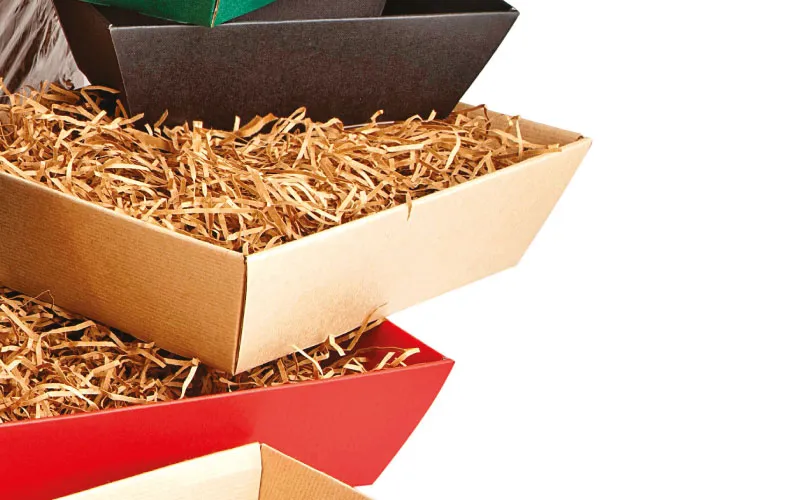 Stack of colorful cardboard boxes filled with brown shredded paper packing material.