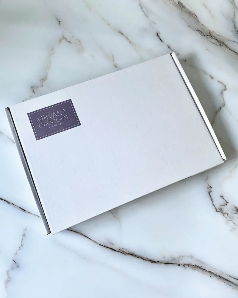 White rectangular box with a purple label reading  on a marble surface.