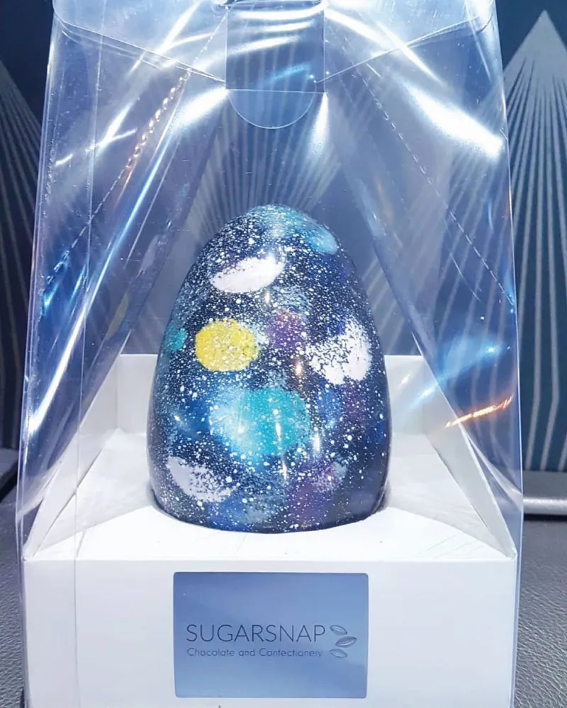Galaxy-themed chocolate egg in clear plastic packaging with a Sugarsnap Chocolate and Confectionery label.