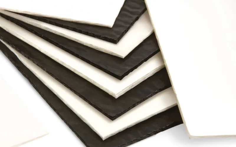 Stack of black and white corrugated foam sheets arranged alternately on a white surface.