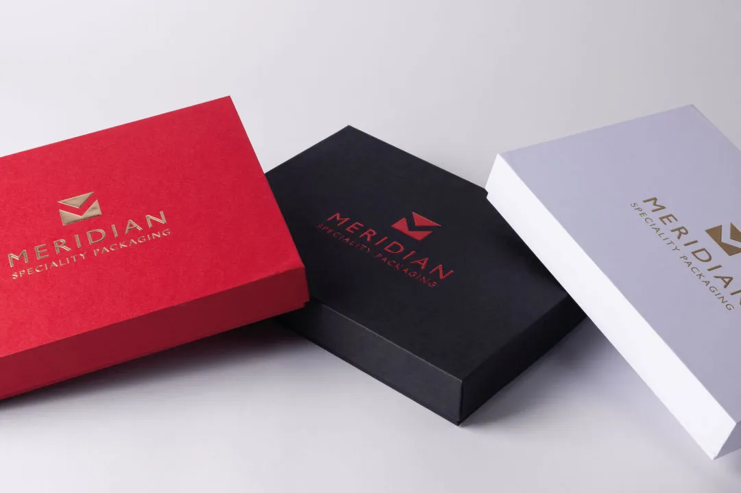 Three rectangular rigid packaging boxes in red, black, and white colors with Meridian Specialty Packaging logo on top.
