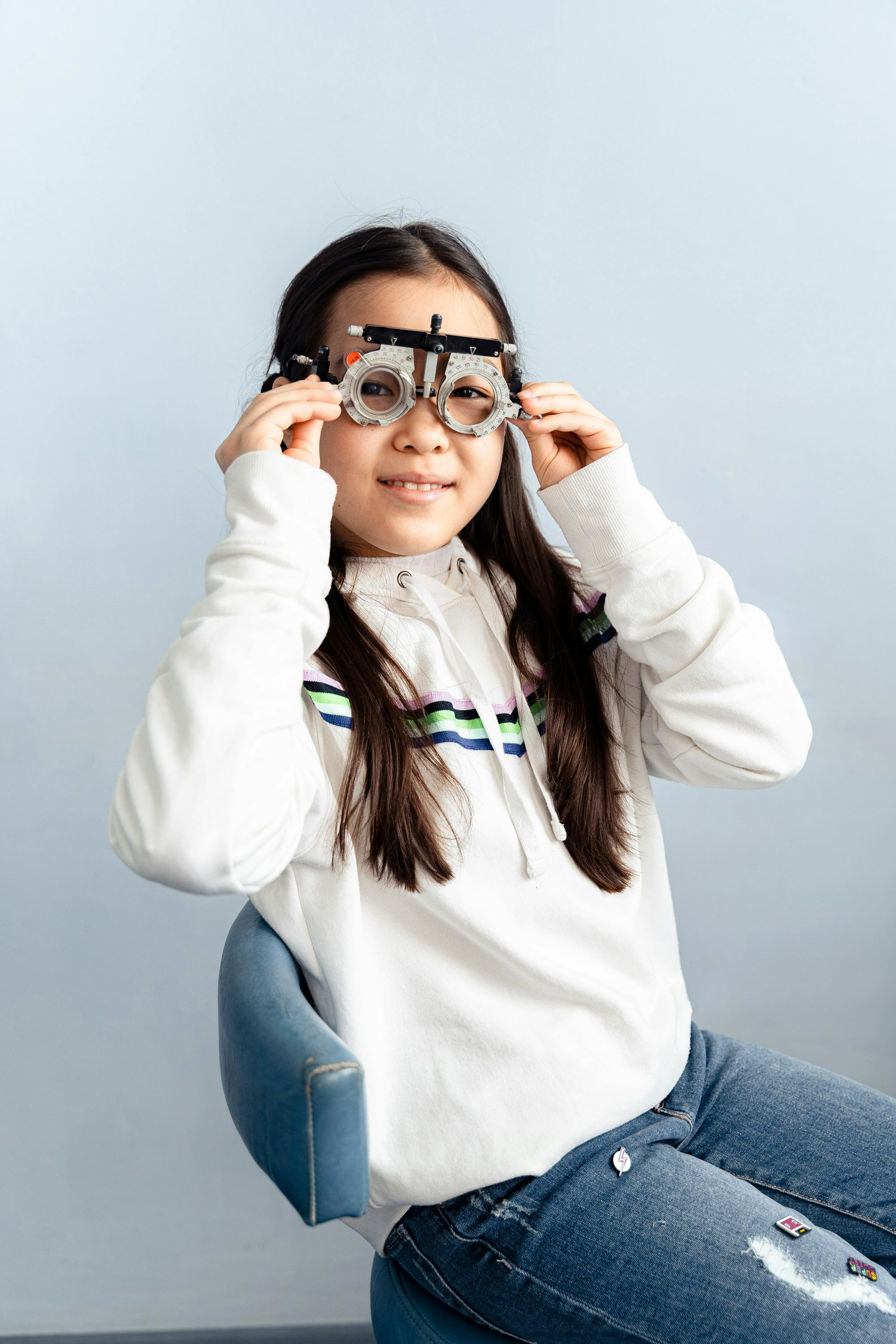 Smiling young person wearing optical testing glasses on blue chair