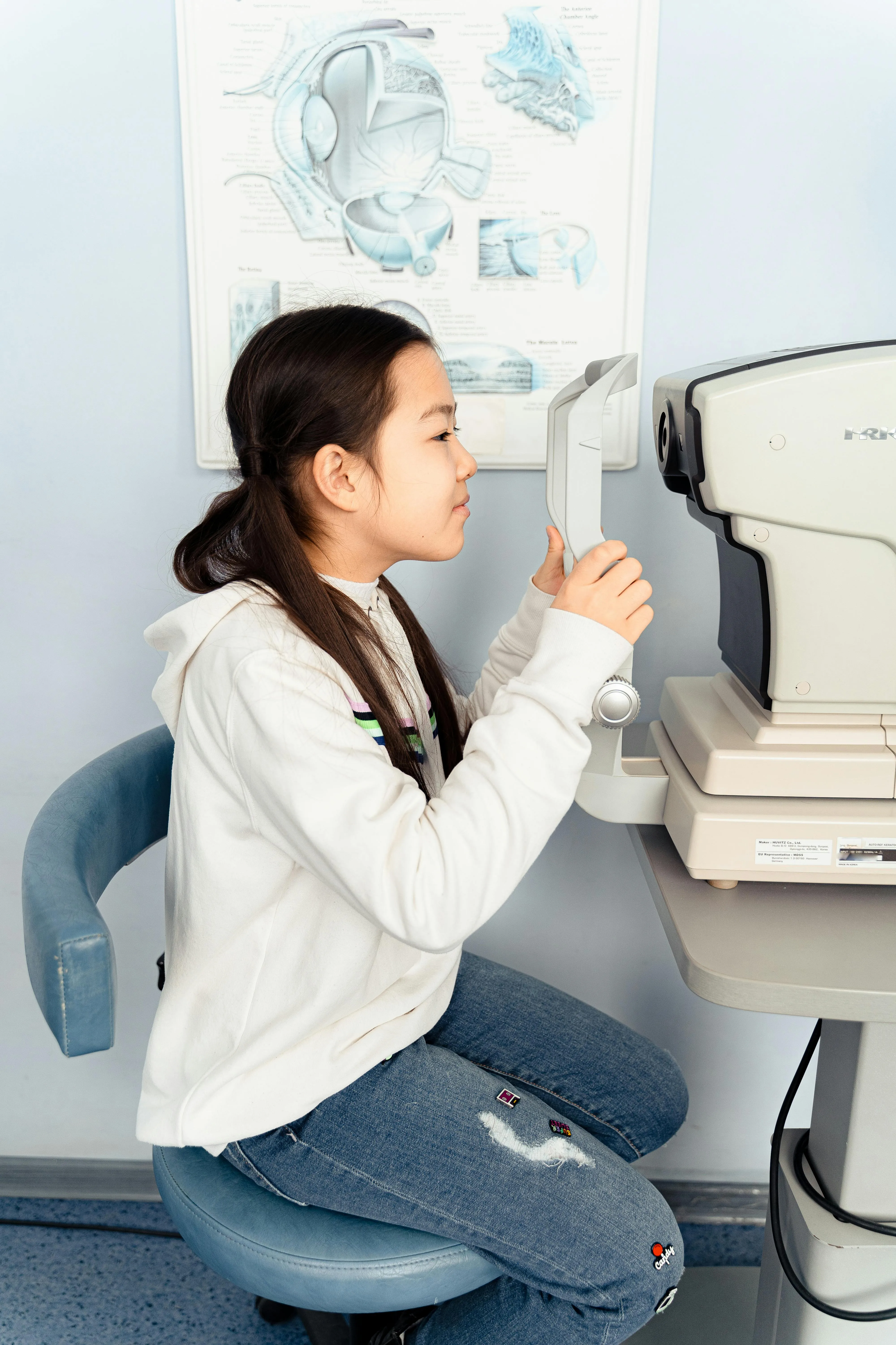 Patient getting eye exam with anatomical eye diagram in background