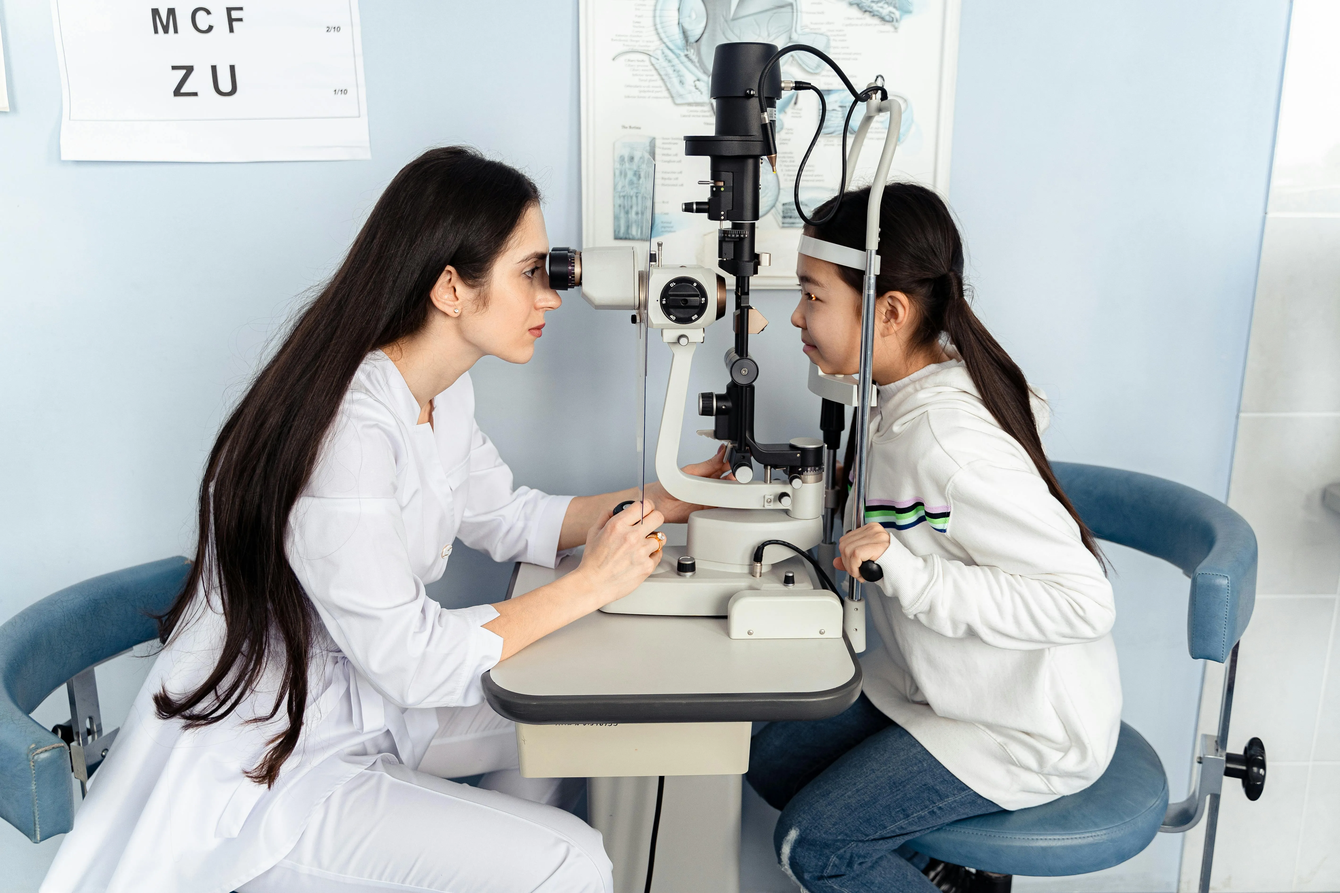 Eye doctor performing eye exam on young patient using slit lamp