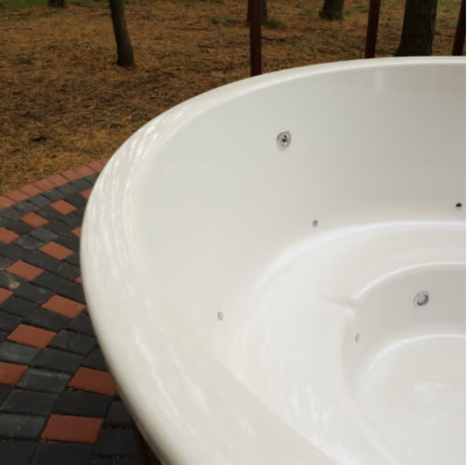 Close-up of an empty white outdoor hot tub surrounded by multicolored interlocking bricks and a forest ground.