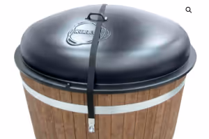 Wooden barrel-shaped grill with a black domed lid secured by a latch strap.