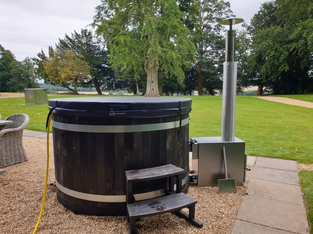 A wood-fired hot tub placed on a gravel base.