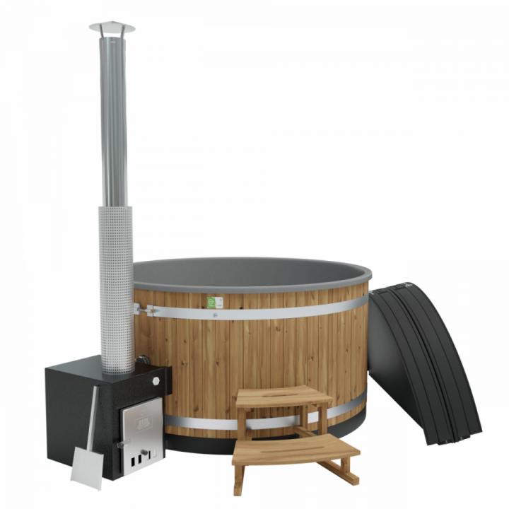 Wooden hot tub with metal stove and chimney, a small wooden step in front, and a black cover leaning against the tub.