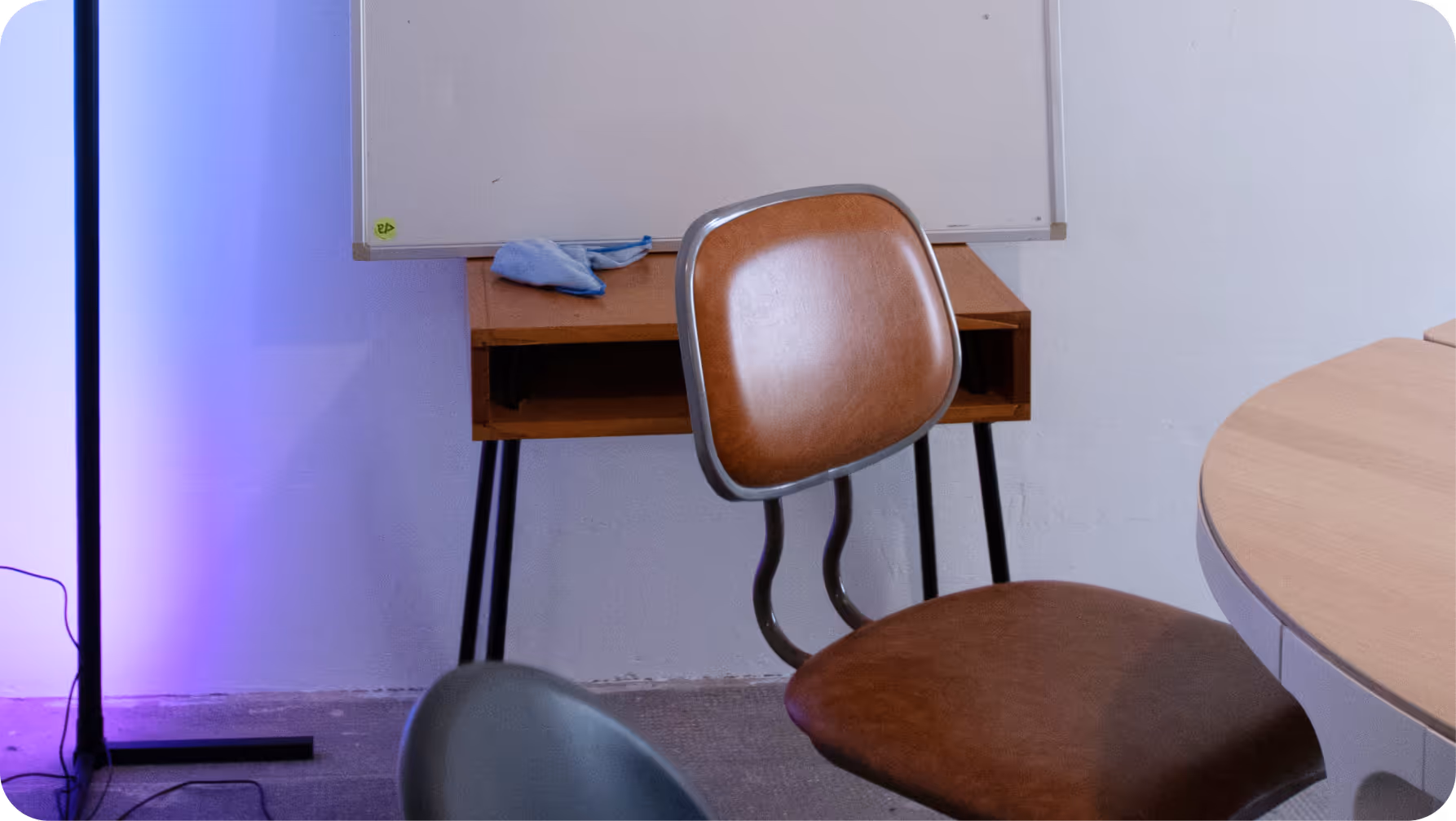 Bürostuhl vor einem Tisch mit Tafel und blauem Licht an weißer Wand.