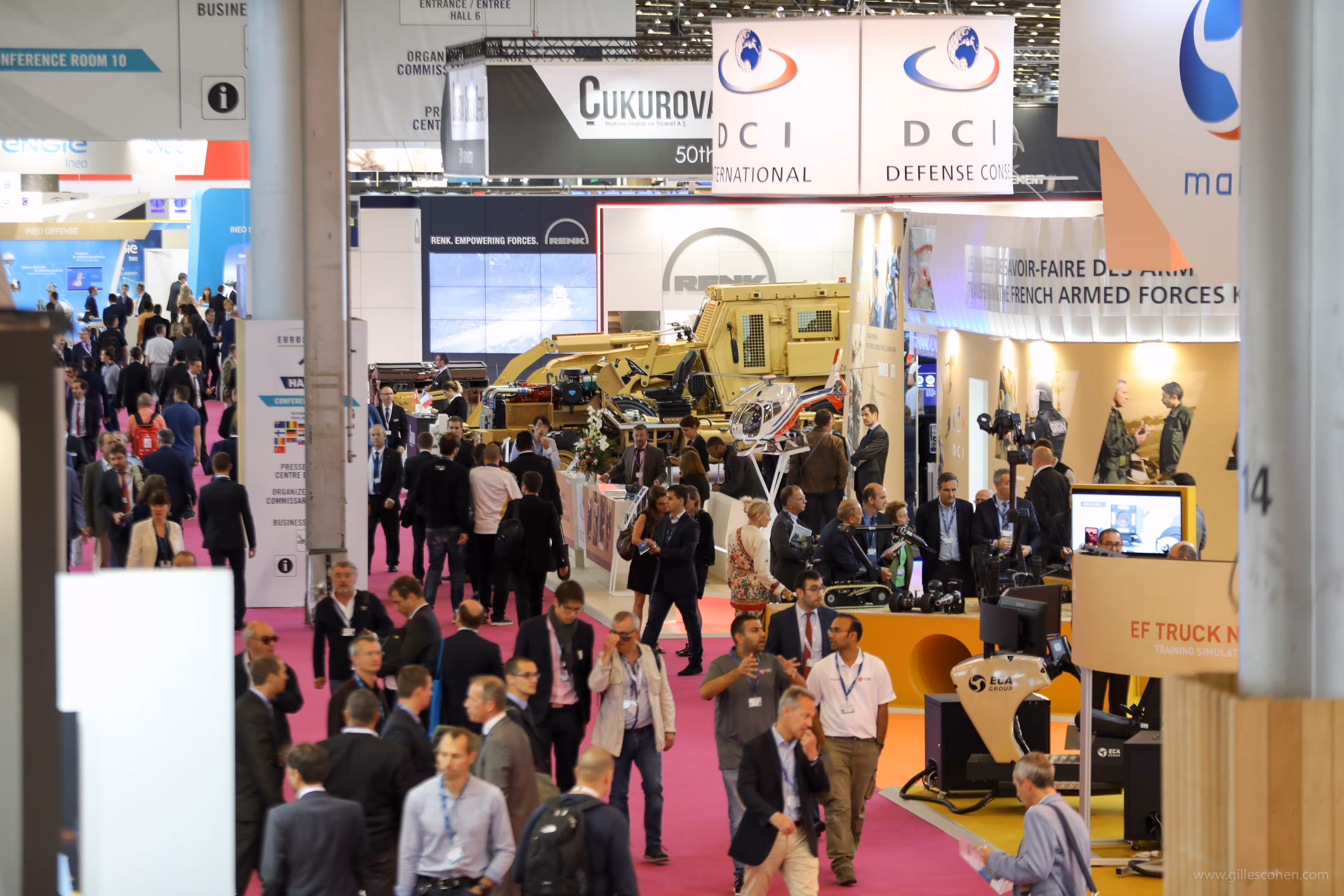 Vue d'un salon professionnel avec foule et stands d'équipement militaire et de défense.