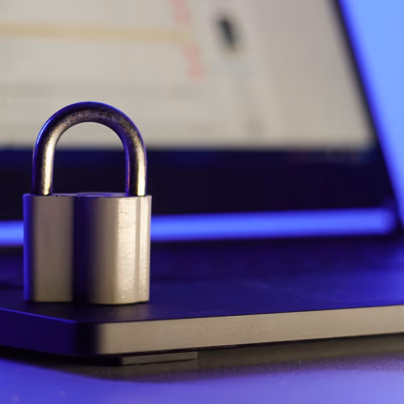 Un cadenas posé sur un ordinateur portable avec un écran flou en arrière-plan.