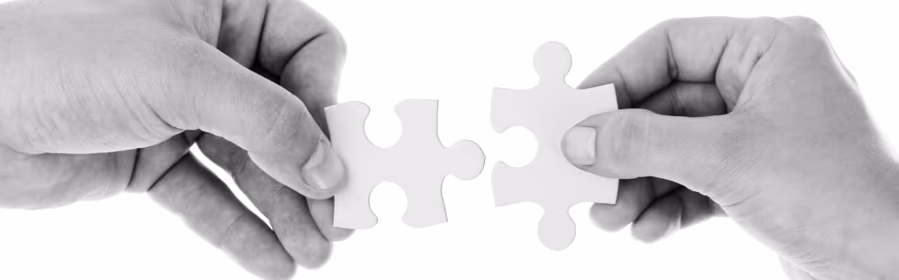 Deux mains tenant deux pièces de puzzle blanches qui s'ajustent l'une à l'autre.