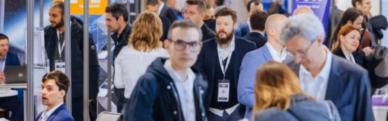 Groupe de professionnels en costumes interagissant lors d’un événement ou salon d’affaires.