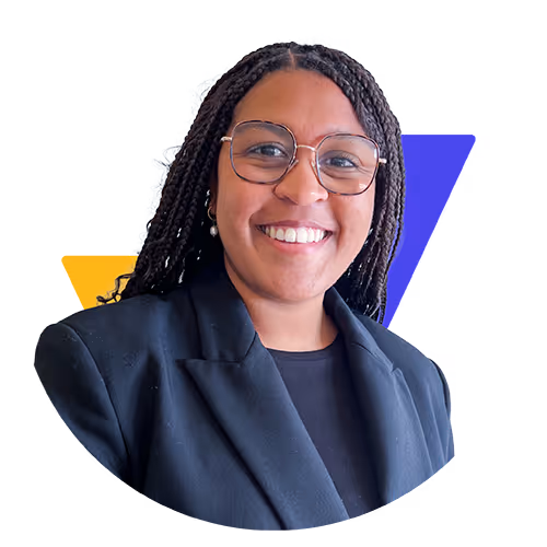 Femme souriante avec lunettes et cheveux tressés portant un blazer noir.