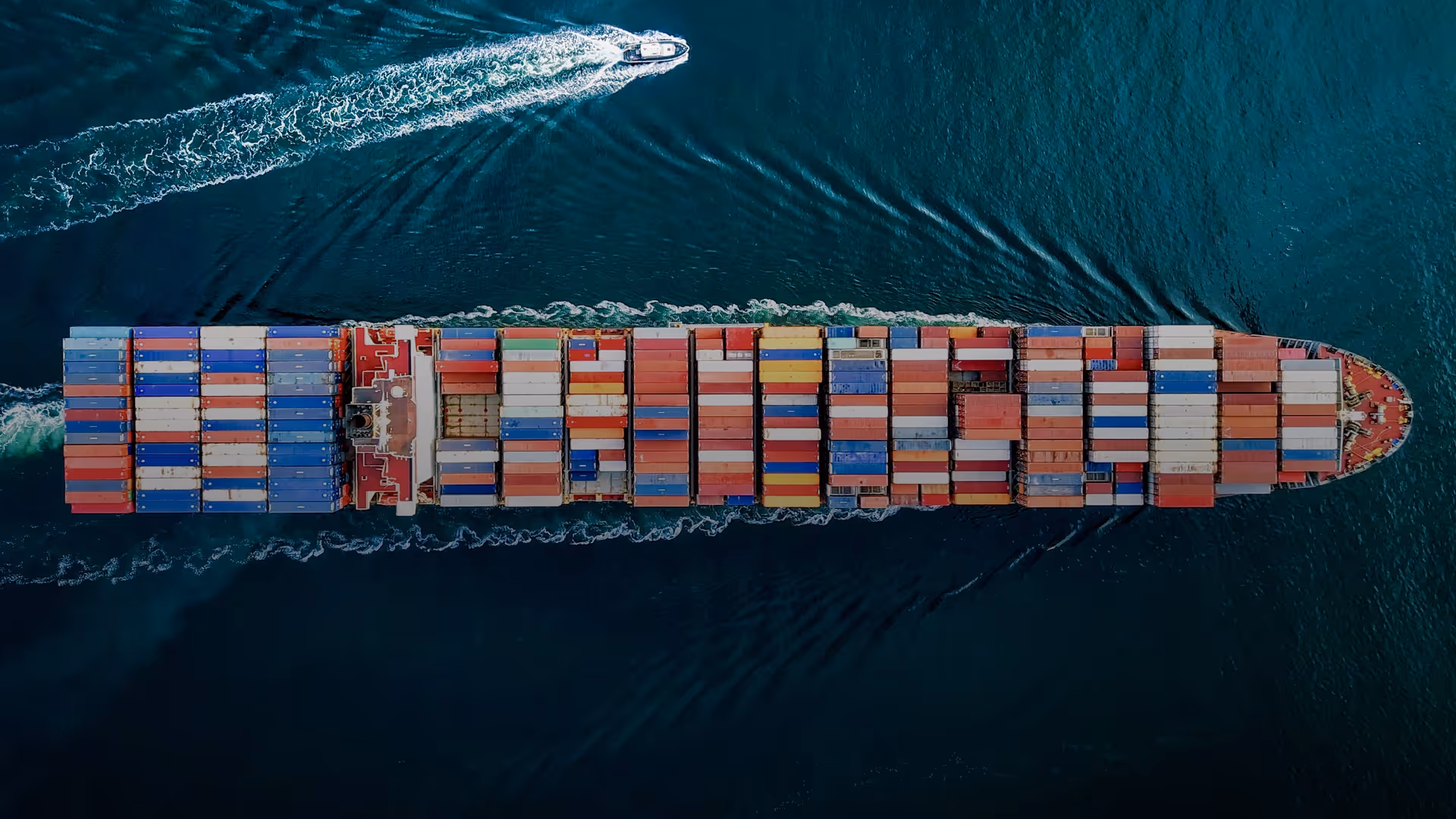 Vue aérienne d'un cargo transportant des conteneurs colorés sur l'eau de mer bleue.