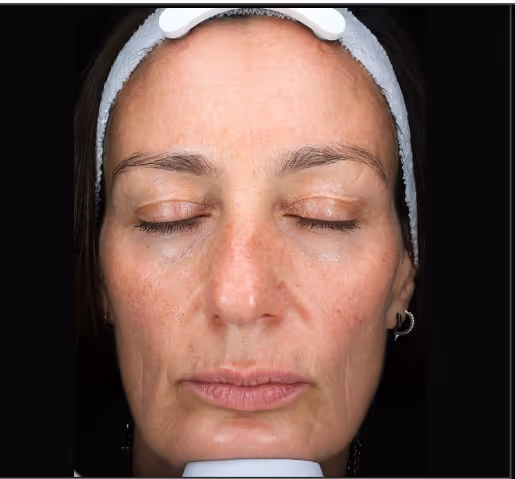 Close-up of a middle-aged woman's face with eyes closed, wearing a gray headband and a small hoop earring.