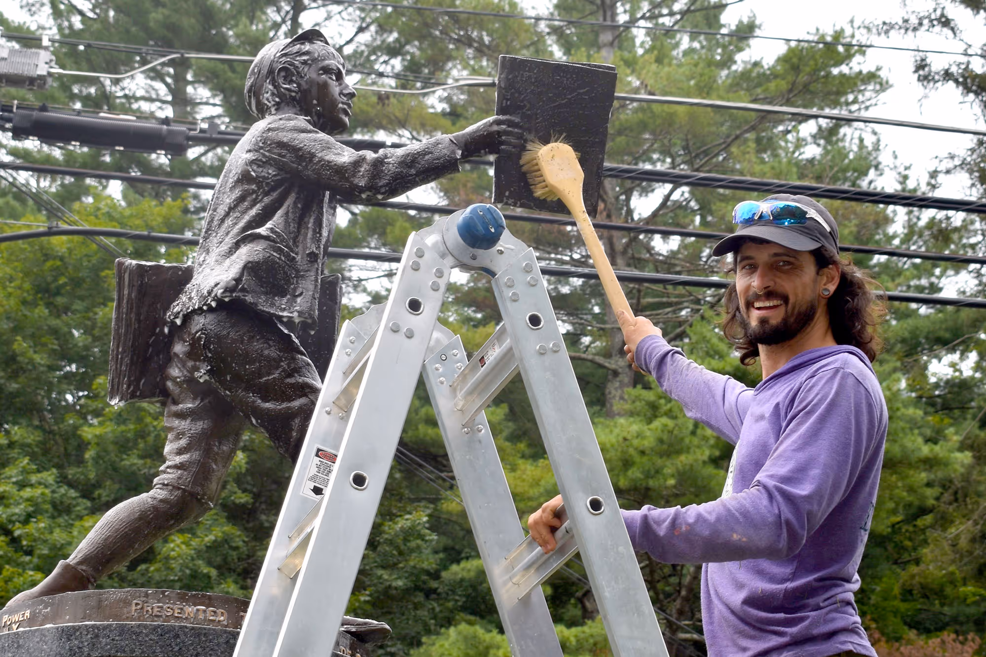 A smiling team member looks at the camera while brush cleaning a sculpture