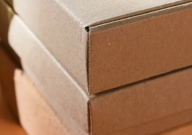 A close-up shot of the corners of two stacked, plain brown cardboard boxes