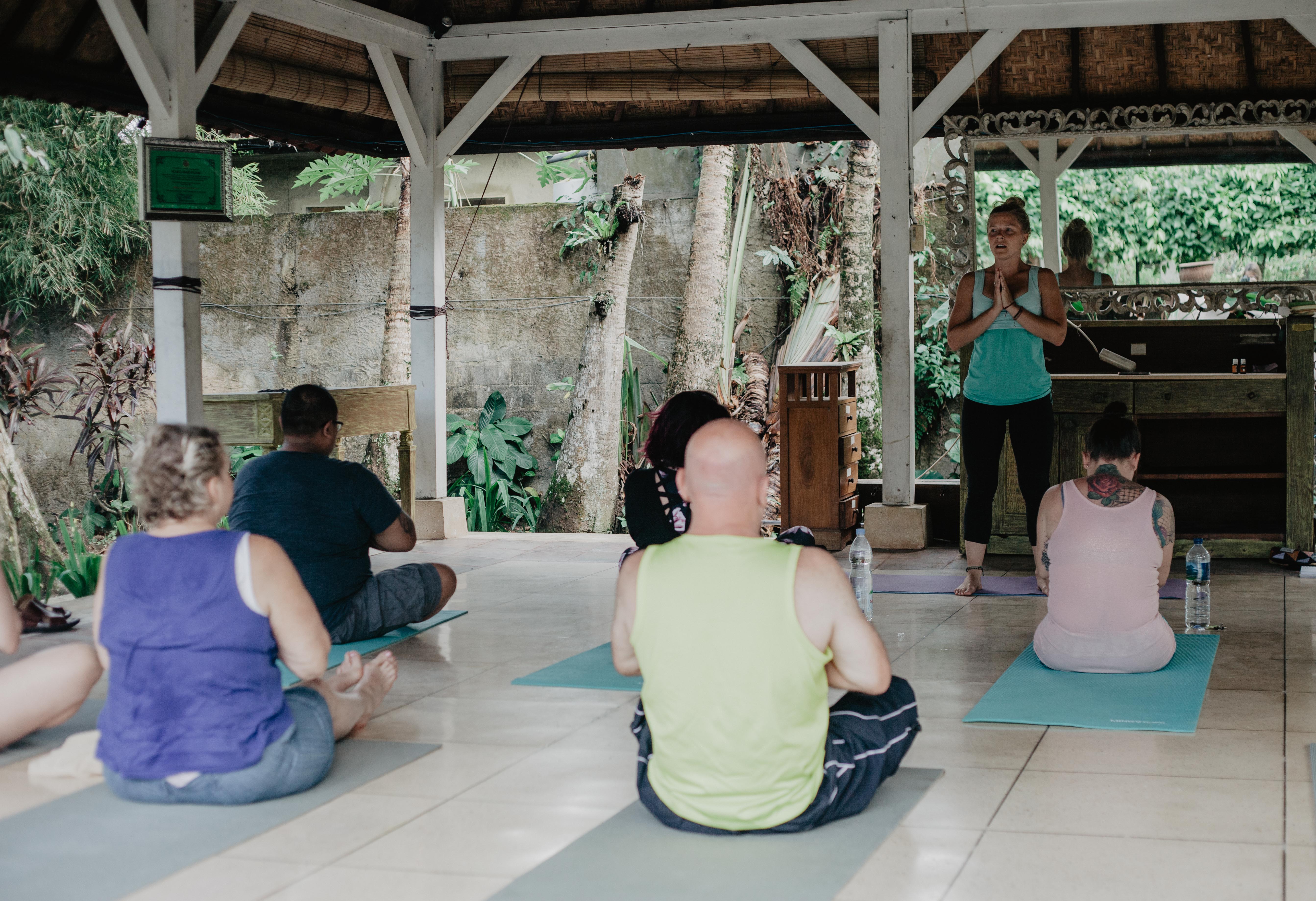 A group seated in an open-air pavilion, being guided in practice