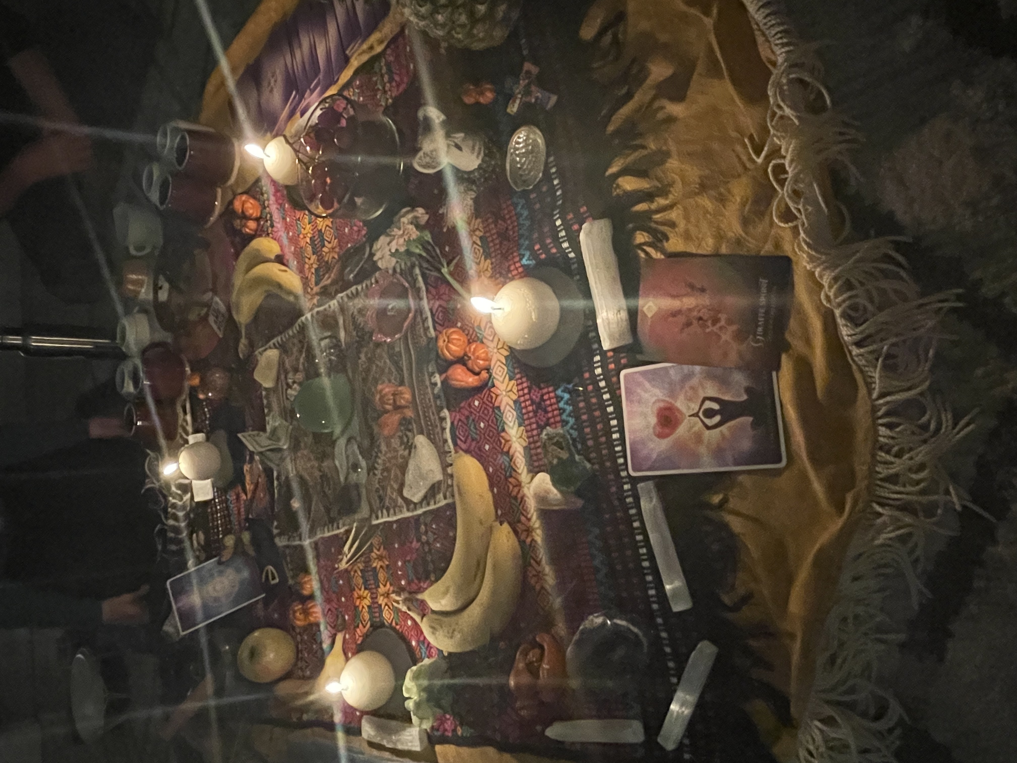 A candlelit altar of flowers, fruit and cards
