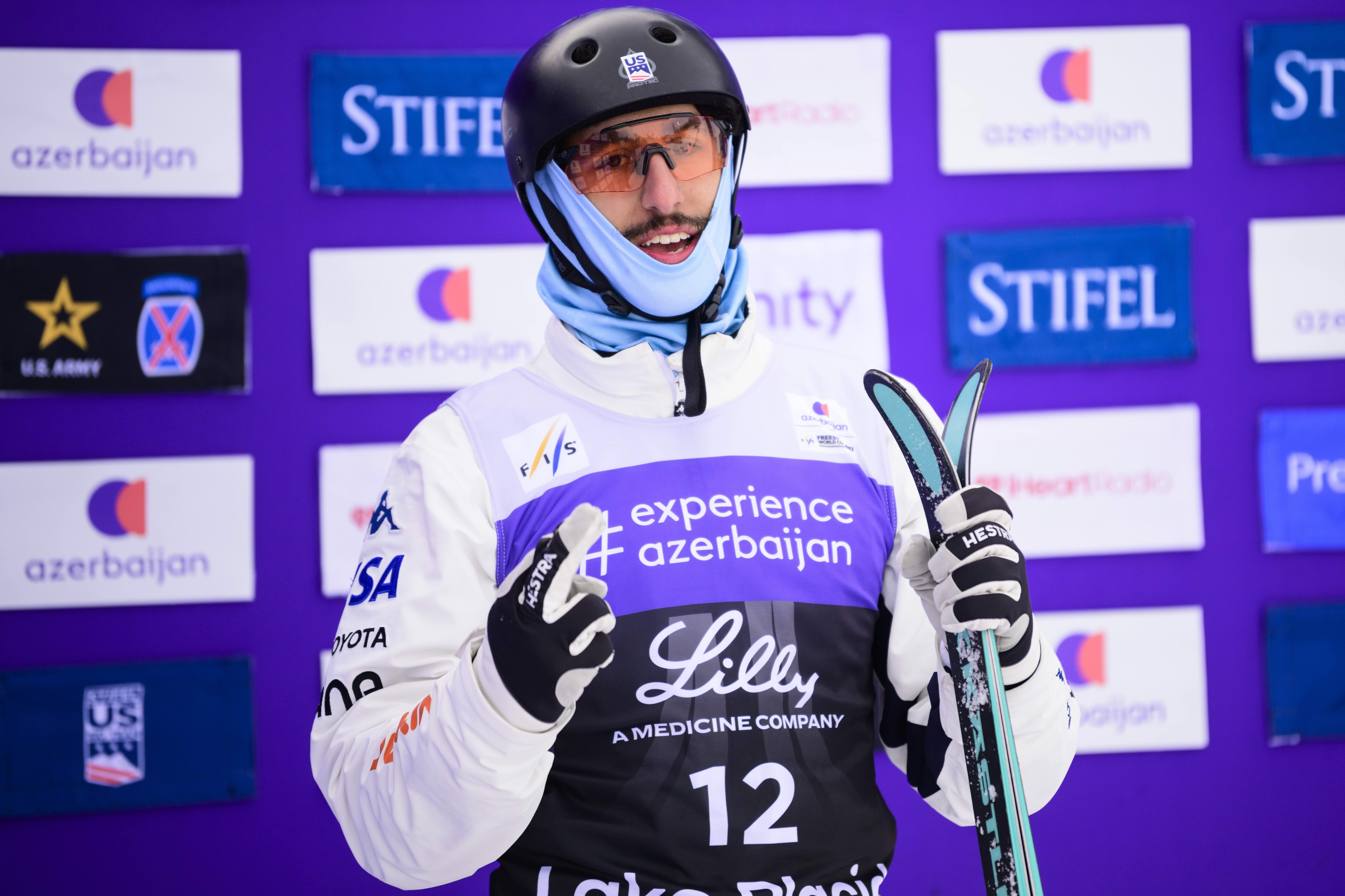 U.S. freestyle aerial skier Ashton Salwan stands at the Lake Placid Olympic Jumping Complex outrun staging gate, smiling as he awaits qualification results.