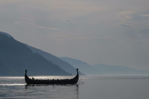 a long boat with two people in it on a lake