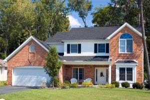 Two-story brick house with green lawn and white block windows