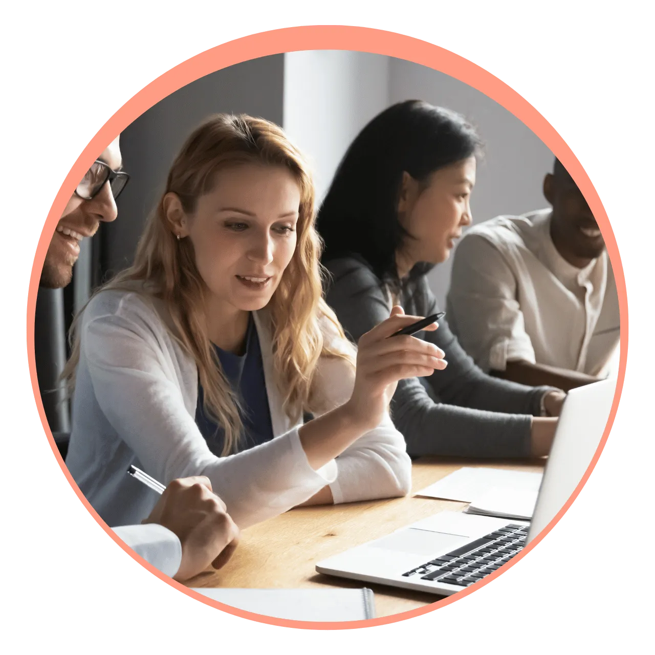 Four diverse colleagues in a meeting room discussing and pointing at a laptop screen.