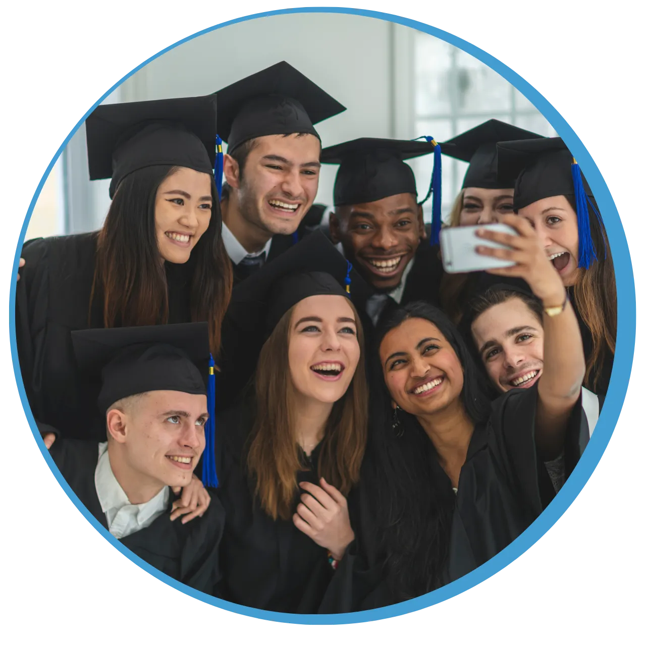 Group of diverse graduates in caps and gowns smiling and taking a selfie together.